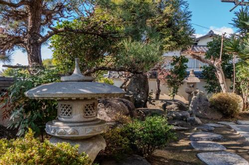 un jardín con un baño de piedra de pájaro en un patio en Tamashima Tea Room – MAX 8ppl, PA / BBQ available, 