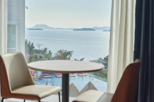 a table and chairs in a room with a view of the ocean at Yeosu Calacatta Hotel & Resort in Yeosu
