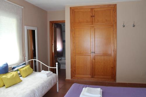 a bedroom with a wooden cabinet and a bed with yellow pillows at Hostal Sabana in San Martín del tesorillo