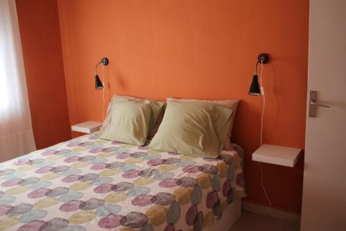 a bedroom with a bed with orange walls and two lamps at Agradable apartamento en Playa La Pineda (Tarragona) in La Pineda