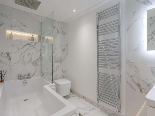a white bathroom with a tub and a toilet at 3 Bed in Harrogate 86490 in Harrogate