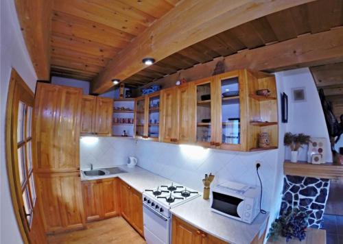 La cuisine est équipée de placards en bois et d'un four avec plaques de cuisson. dans l'établissement Domcek v strani, à Mýto pod Ďumbierom