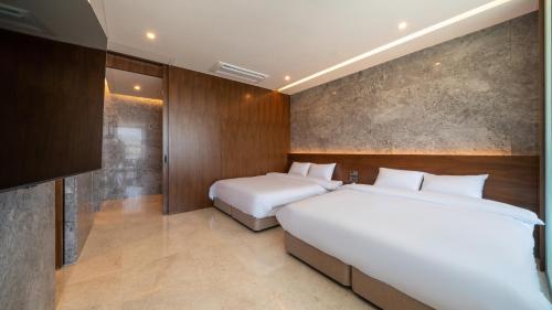 a bedroom with two beds and a television in it at Yeosu Calacatta Hotel & Resort in Yeosu