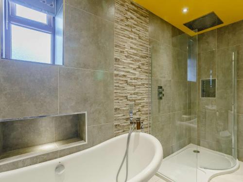 a bathroom with a tub and a glass shower at 5 Bed in Haworth 88390 in Oxenhope