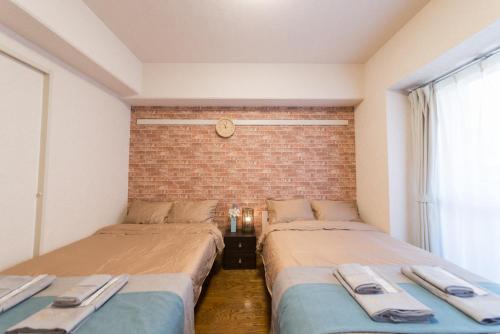 dwa łóżka w pokoju z ceglaną ścianą w obiekcie nestay apartment tokyo akihabara w Tokio