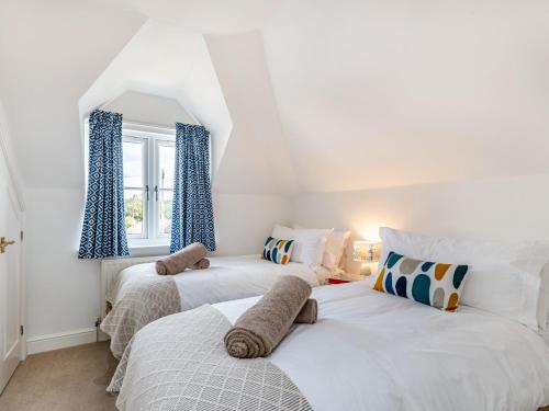 two beds in a white room with blue curtains at 2 Bed in Sheringham 88076 in Sheringham