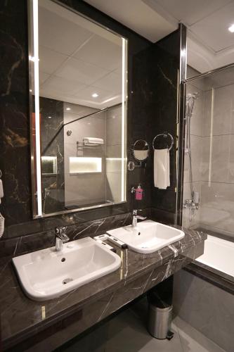 a bathroom with two sinks and a mirror and a tub at Concorde Creek View Hotel Bur Dubai in Dubai