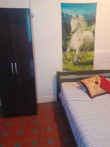 1 dormitorio con 1 cama y una pintura de un caballo en Posada atlantida, en Atlántida