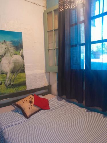 1 dormitorio con 1 cama y una pintura de un caballo en Posada atlantida, en Atlántida