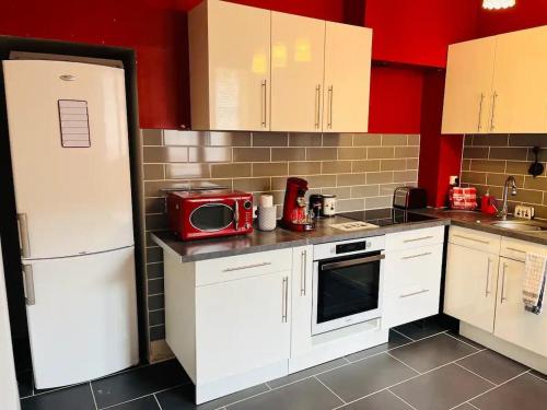 a kitchen with white cabinets and a red microwave at Bienvenue l'Opale Boulogne in Boulogne-sur-Mer