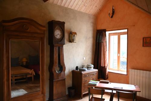 een kamer met een grootvaders klok en een tafel bij Le Deyran in Égliseneuve-dʼEntraigues