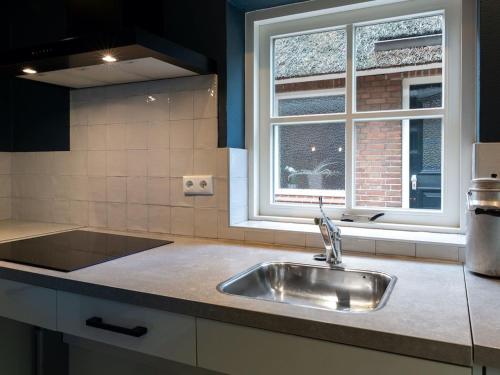 eine Küche mit einem Waschbecken und einem Fenster in der Unterkunft Attractive holiday home with a wood stove, located on a farm in Heeten