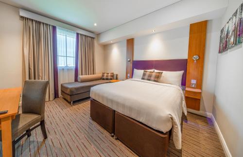 a hotel room with a bed and a desk at Premier Inn Dubai International Airport in Dubai