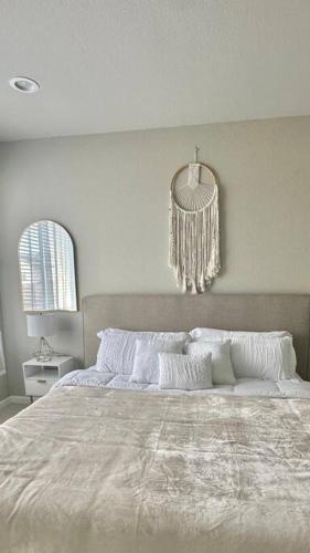 a white bedroom with a large bed and a chandelier at Bohemian Bliss 10 Min from DT SJ in San Jose