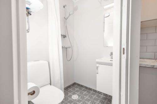 La salle de bains blanche est pourvue d'une douche et de toilettes. dans l'établissement Kapelludden Camping & Stugor, à Borgholm