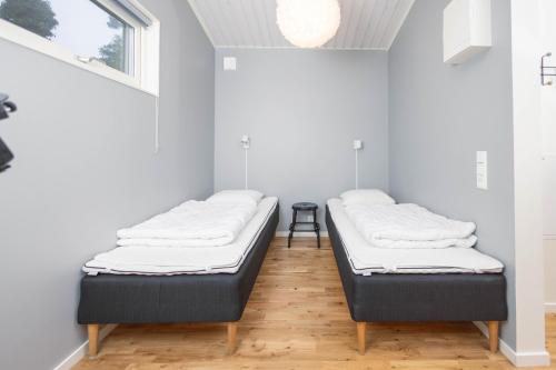 2 Betten in einem Zimmer mit weißen Wänden und Holzböden in der Unterkunft Kapelludden Camping & Stugor in Borgholm