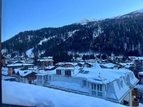 a town covered in snow with a mountain in the background at Mansarda delle Dolomiti nuovissimo appartamento in Madonna di Campiglio