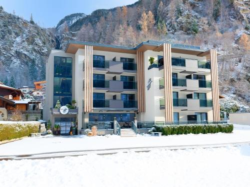 a building in the snow in front of a mountain at VIER Studios & Restaurant in Längenfeld