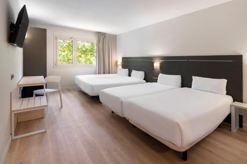 een hotelkamer met 2 bedden en een televisie bij B&B HOTEL Barcelona Rubí in Rubí