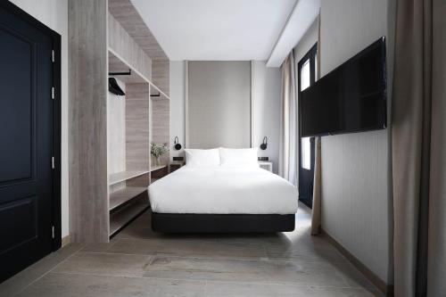 a bedroom with a white bed and a flat screen tv at numa I Luna Apartments in Madrid