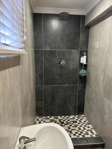 a bathroom with a shower with a tub and a sink at Le Rosette Residence in Empangeni
