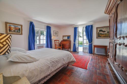 a bedroom with a bed with blue curtains and a desk at Le Clos du Pertuis in La Flotte