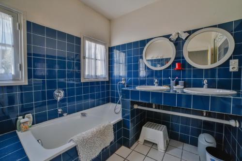 a blue tiled bathroom with two sinks and a tub at Le Clos du Pertuis in La Flotte
