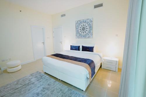 a white bedroom with a large bed with blue accents at Citi home 1BR New Marina Sulafa Tower in Dubai