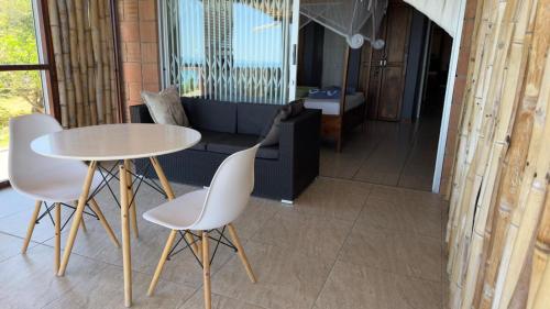 a table and chairs in a room with a couch at Peri-Peri Divers B&B Morrungulo in Cabo Nhabacal