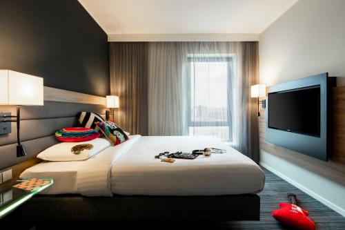 a hotel room with a large bed and a flat screen tv at Moxy Glasgow SEC in Glasgow