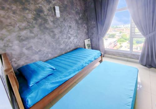 łóżko z niebieską pościelą w pokoju z oknem w obiekcie SkyHome @ D'Perdana Kota Bharu w mieście Kota Bharu