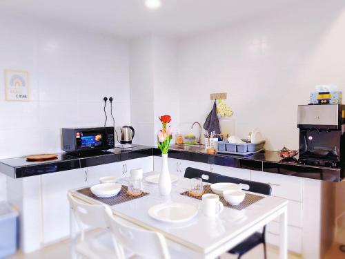 a kitchen with a white table with a vase of flowers at SkyHome @ D'Perdana Kota Bharu in Kota Bharu