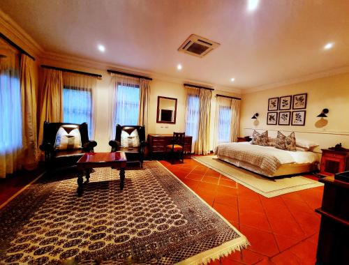 a bedroom with a bed and a table and chairs at Budmarsh Country Lodge in Magaliesburg