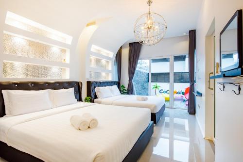 two beds in a hotel room with a tv at Cocomelon Poolvilla1 in Hua Hin