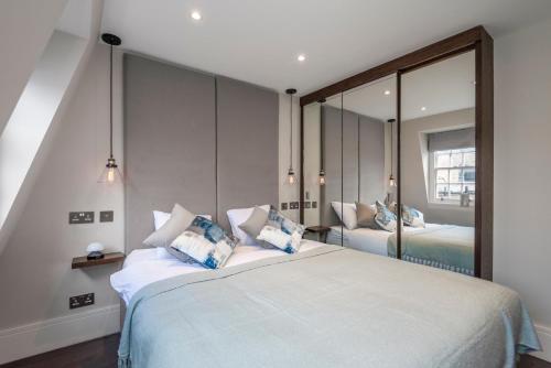 a bedroom with two beds and a large mirror at Luxury Georgian House in Marylebone: Modern 1-Bed Retreat in London