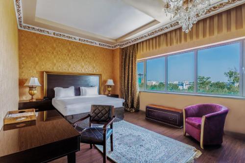 um quarto de hotel com uma cama, uma secretária e uma cadeira em Darhan Boutique Hotel em Tashkent