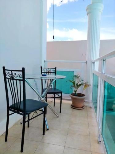 einen Balkon mit einem Glastisch und 2 Stühlen in der Unterkunft Appartement calme à Calodyne proche de la plage in Calodyne