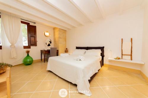 sypialnia z białym łóżkiem i stołem w obiekcie Masseria Tenuta Le Menze w mieście Cavallino