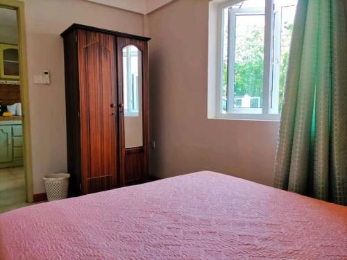 ein Schlafzimmer mit einem Bett, einer Kommode und einem Fenster in der Unterkunft Appartement calme à Calodyne proche de la plage in Calodyne