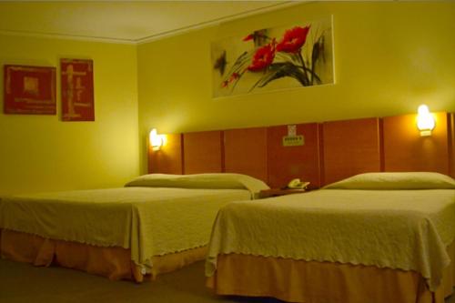 two beds in a hotel room with yellow walls at Barbur Plaza Hotel in Ponta Grossa