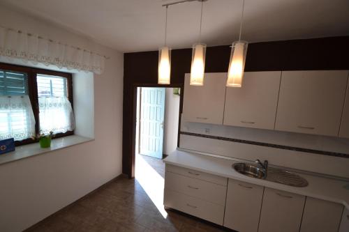 a kitchen with white cabinets and a sink and a window at Villa Pistan in Murvica