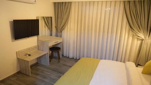 una camera d'albergo con letto, scrivania e TV di Talles Comfort Boutique Hotel - Alaçatı - Adult Only ad Alaçatı