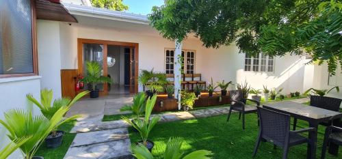 un jardín con mesa y sillas frente a una casa en Turtle Inn Dharavandhoo, en Dharavandhoo