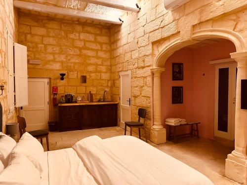 sypialnia z łóżkiem i kamienną ścianą w obiekcie Talbot House by Talbot & Bons w mieście Luqa