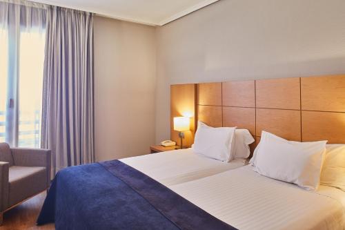 a hotel room with a bed and a chair at Silken Ciudad de Vitoria in Vitoria-Gasteiz