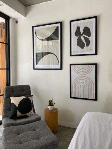ein Wohnzimmer mit einem Stuhl und Bildern an der Wand in der Unterkunft The CIVYT in Ubud