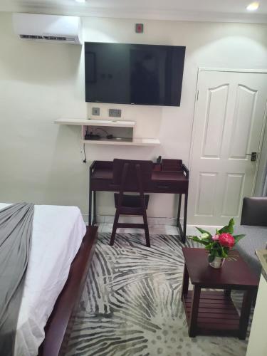 a room with a bed and a desk and a television at Lovely 1 bedroom self catering apartment in Lusaka