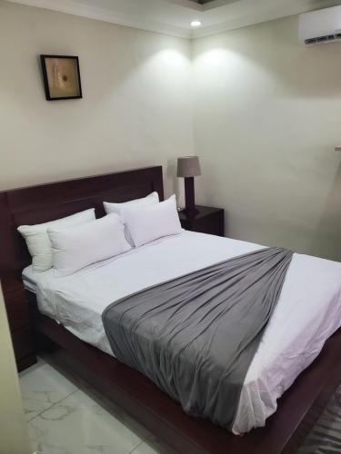 un letto con lenzuola e cuscini bianchi in una stanza di Lovely 1 bedroom self catering apartment a Lusaka