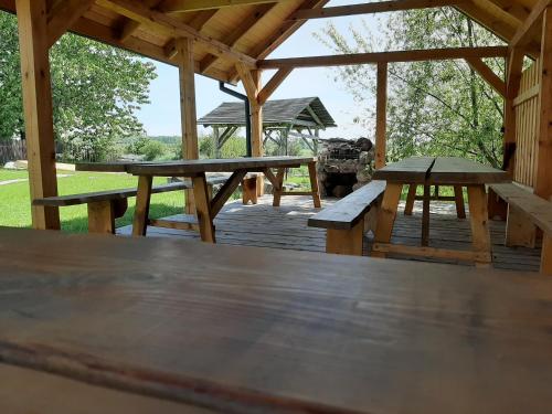 a wooden deck with picnic tables and a gazebo at Willa Kumat in Brańsk