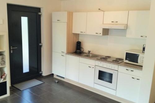 a kitchen with white cabinets and a black door at Schicke u. moderne FeWo zum Odenwald in Gorxheim